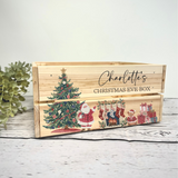 A personalized wooden Christmas Eve box with a natural wood finish, decorated with illustrations of a Christmas tree, Santa Claus, stockings, and gifts. The front features the text 'Charlotte's CHRISTMAS EVE BOX' in black script and block lettering.